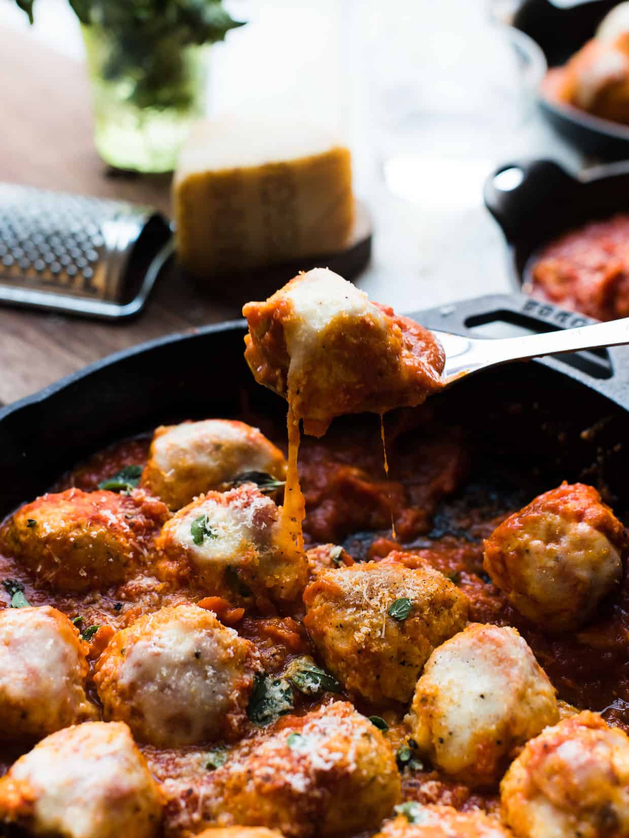 Chicken Parmesan Meatballs with melted cheese being served from a cast iron skillet