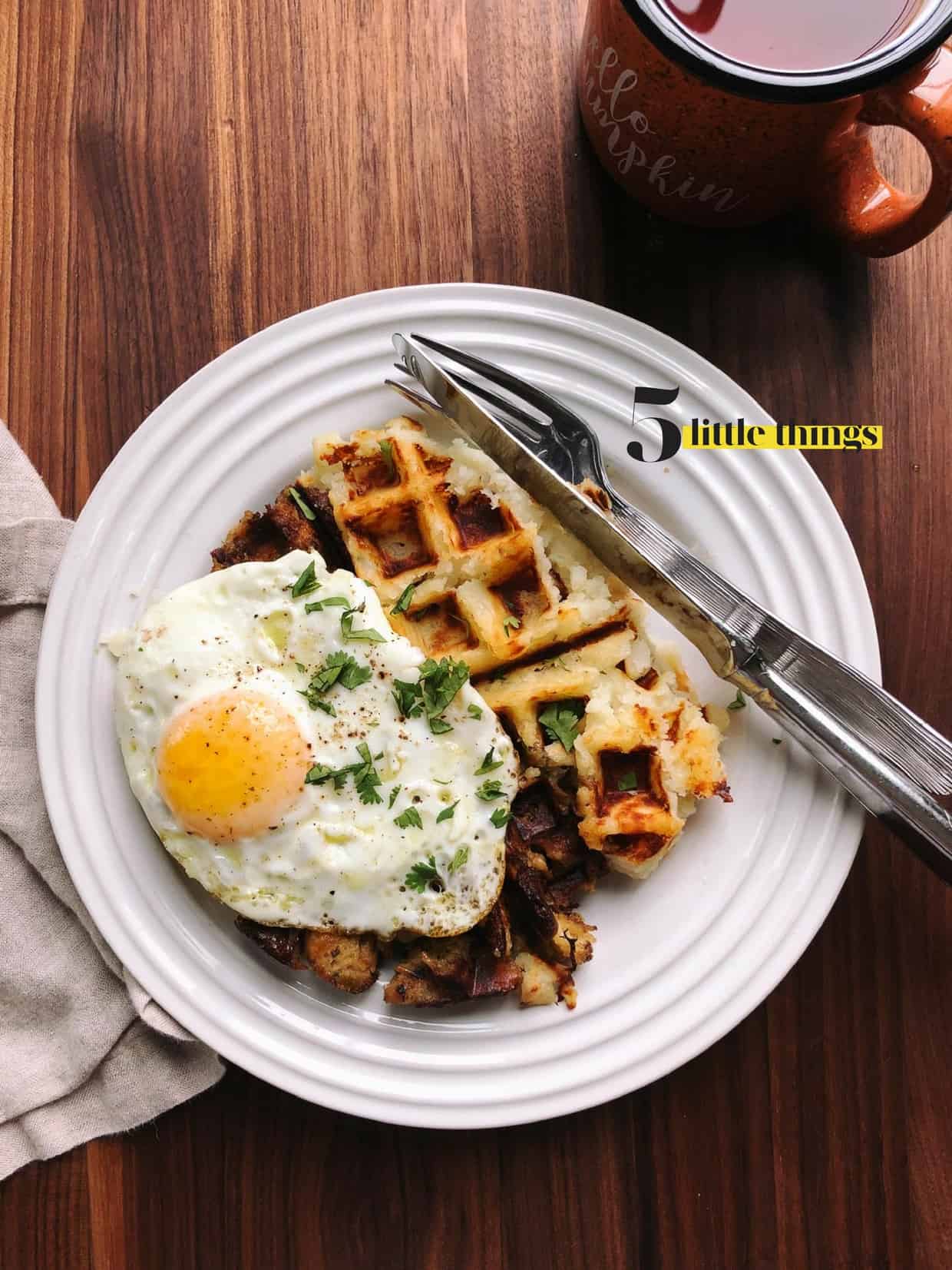 Waffle with a fried egg on top served on a white plate.