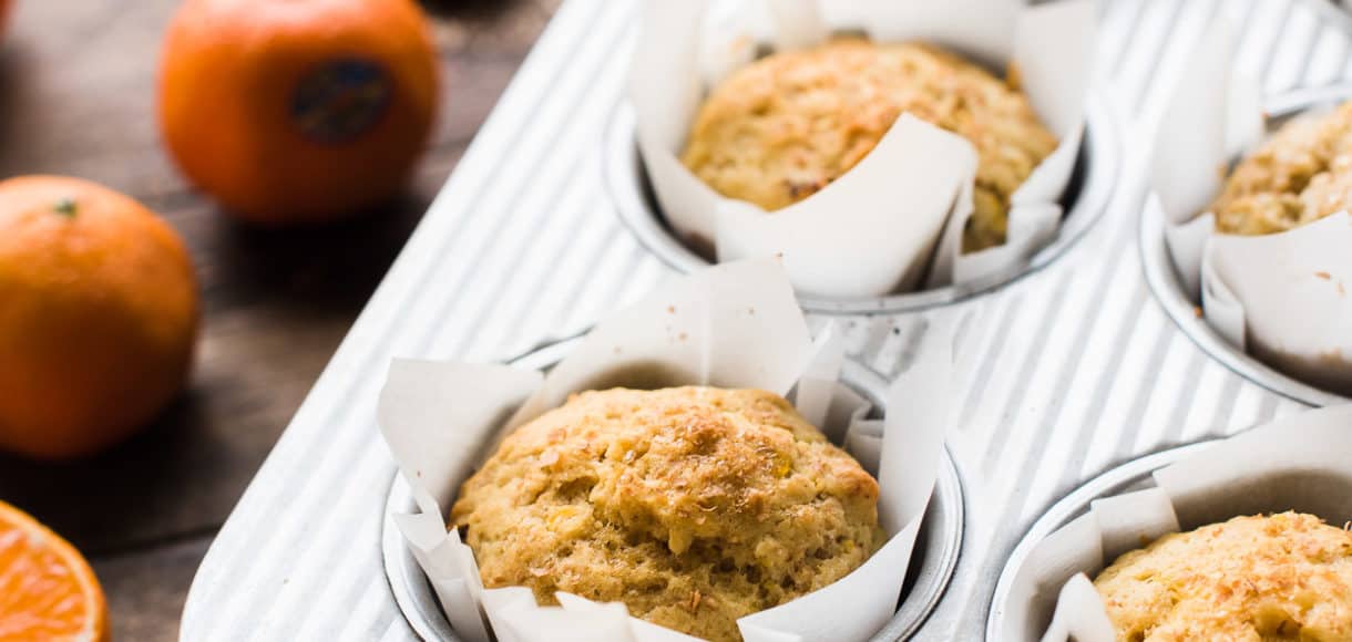 Muffins with mandarin oranges, ginger and dates in a muffin pan.