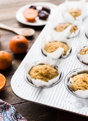 Muffins with mandarin oranges, ginger and dates in a muffin pan.