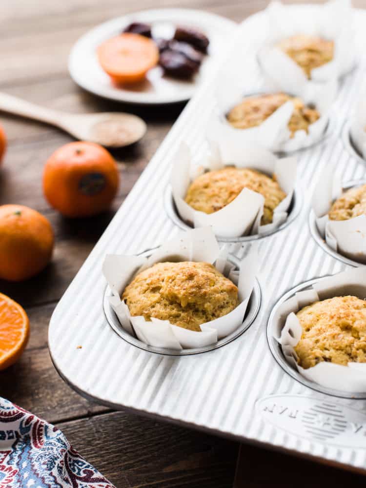 Muffins with mandarin oranges, ginger and dates in a muffin pan.