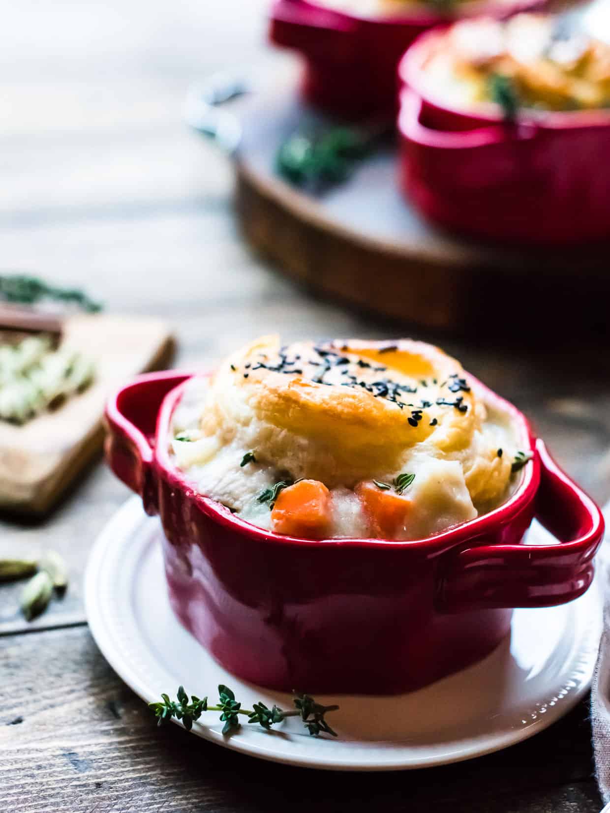 individual serving of chicken pot pie with puff pastry crust in a red serving dish