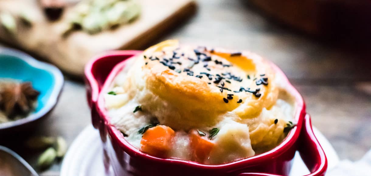 chicken pot pie with a puff pastry crust in a red ramekin.