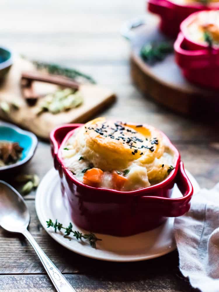 chicken pot pie with a puff pastry crust in a red ramekin.