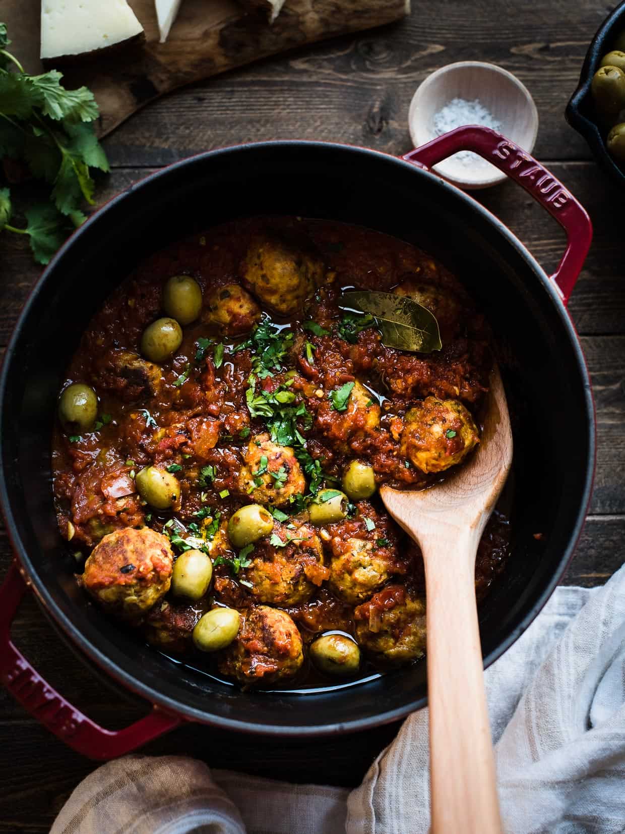 Albondigas with Olives in tomato sauce in a red Staub Dutch oven.