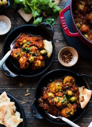 Albondigas with Olives in tomato sauce in black cast iron dishes.