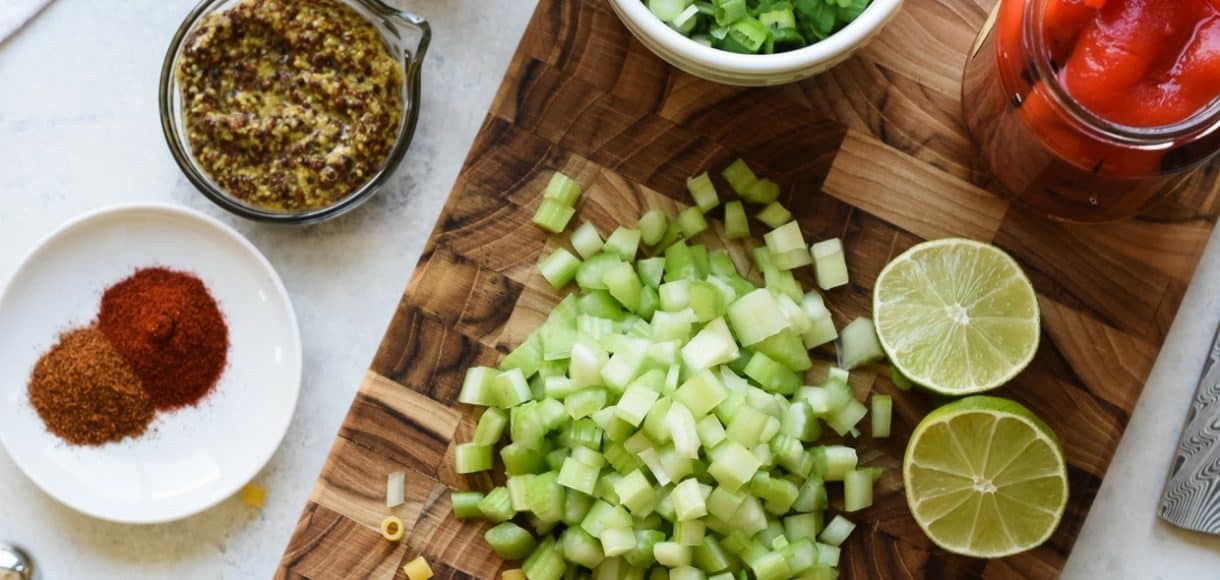 Cutting board with sliced celery, lime and spices.