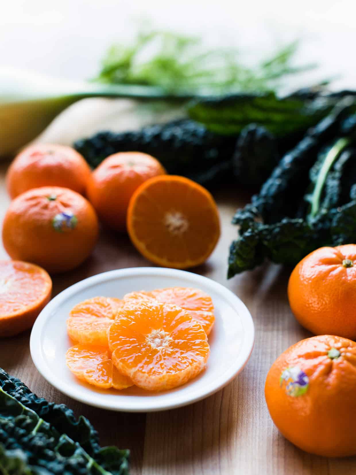 slices of Halos Mandarin Oranges on a white plate with kale in the background