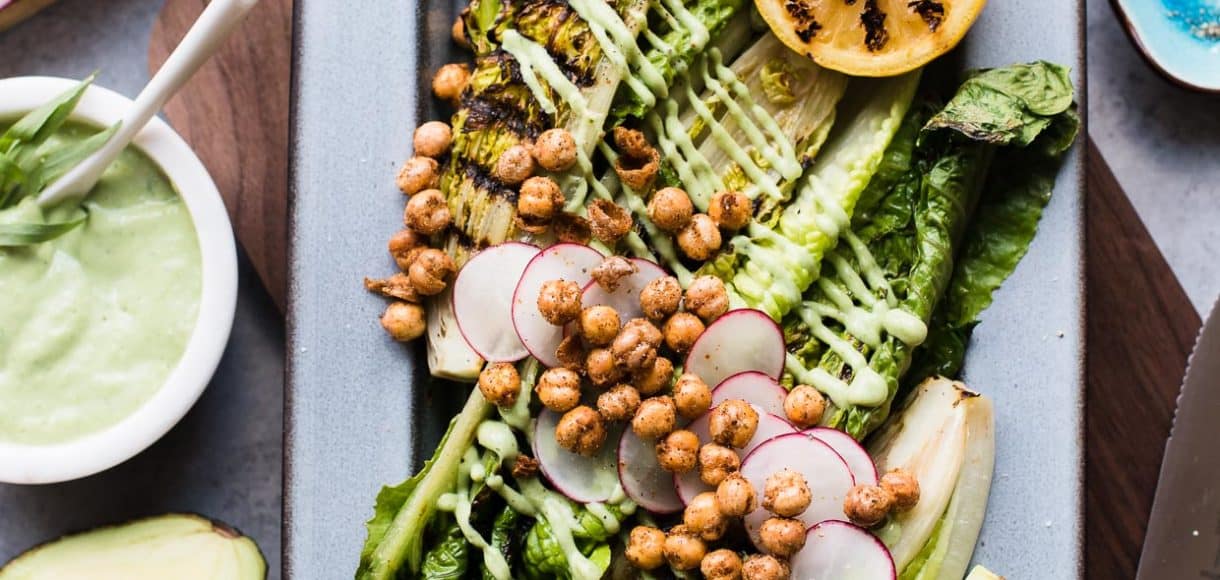 Grilled Romaine Green Goddess Salad on grey platter with avocado, radish, chickpeas and grilled lemon.