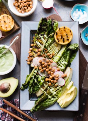 Grilled Romaine Green Goddess Salad on grey platter with avocado, radish, chickpeas and grilled lemon.