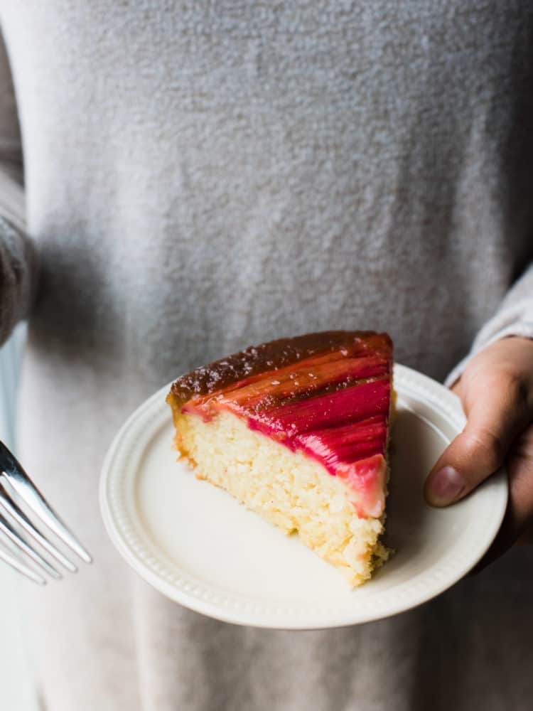 Holding a slice of Rhubarb Upside-Down Cake on a plate.