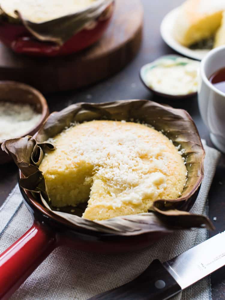 Bibingka - Filipino Coconut Rice Cake baked in banana leaves in a red terra cotta dish.