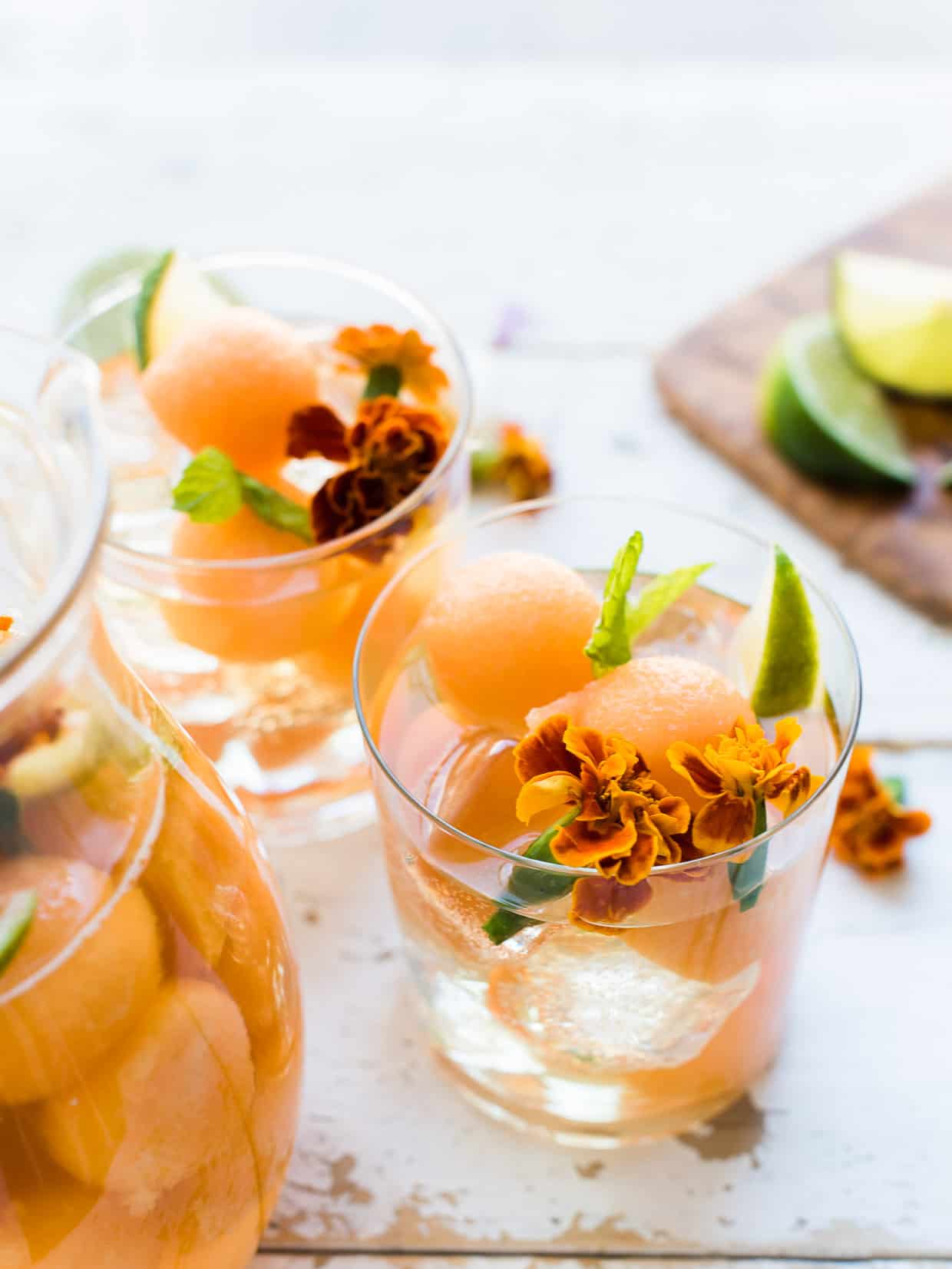 Glasses of Ginger Cantaloupe Sangria garnished with mint and edible flowers