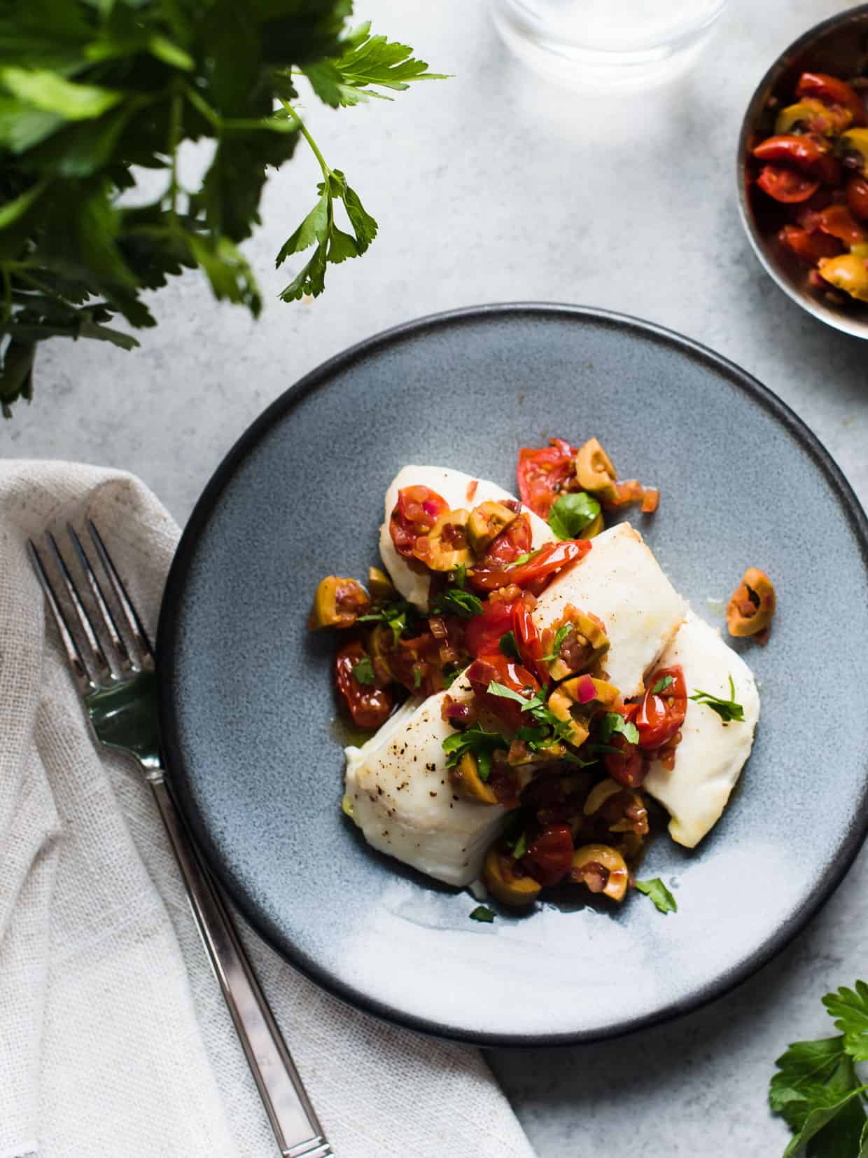 Baked halibut topped with a sauce of olives, onions, tomato and parsley.
