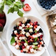 Strawberries, blueberries, and crispy jicama come together for a super simple, patriotic, and barbecue-ready Red, White and Blue Berry Jicama Salad in a white bowl.