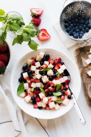 Strawberries, blueberries, and crispy jicama come together for a super simple, patriotic, and barbecue-ready Red, White and Blue Berry Jicama Salad in a white bowl.