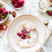 Bowl of Chai Coconut Brown Rice Pudding with strawberries, raspberries, flaxseed, pecan nuts for breakfast.