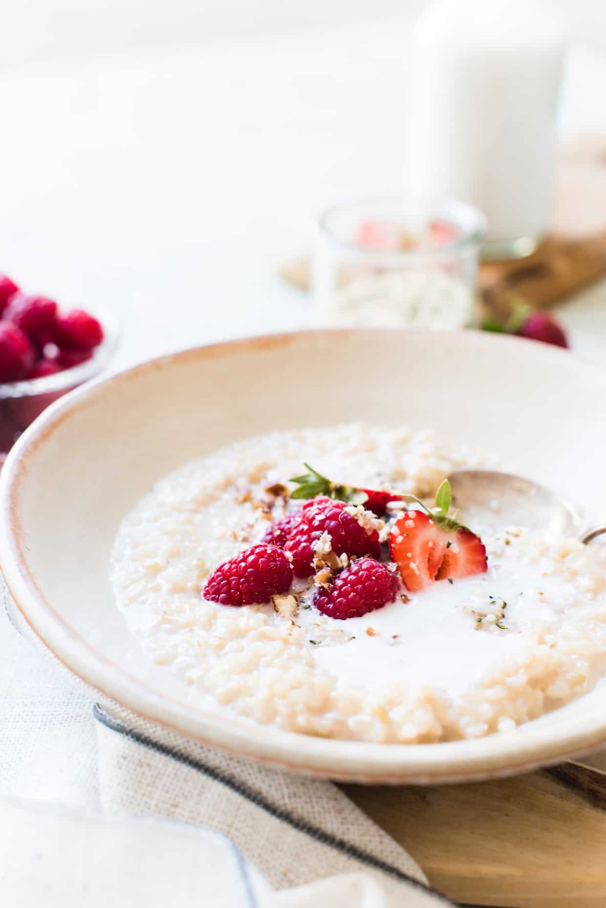 A bowl of Chai Coconut Brown Rice Pudding in bowl with fresh berries and coconut milk.