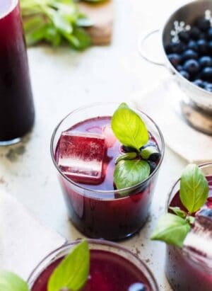 Glasses of Blueberry Ginger Basil Soda garnished with basil.