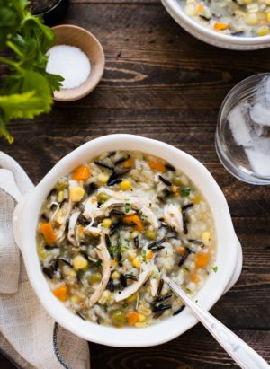 A bowl of Pressure Cooker Creamy Rotisserie Chicken and Wild Rice Soup in a white bowl on wood table.