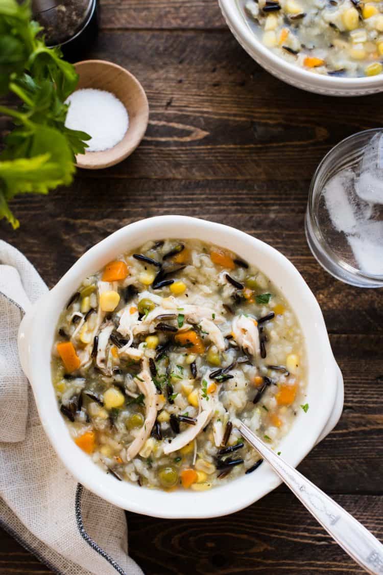 A bowl of Pressure Cooker Creamy Rotisserie Chicken and Wild Rice Soup in a white bowl on wood table.