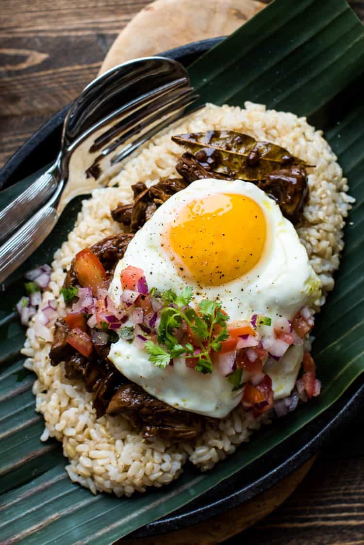 Adobo Chicken Loco Moco on a banana leaf with tomato onion relish.