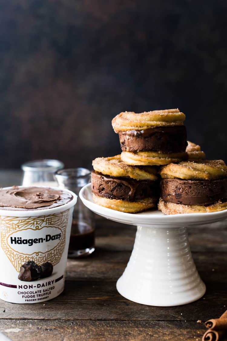 Baked Churro Baked Churro Ice Cream Sandwiches made with Häagen-dazs non-dairy Chocolate Salted Fudge Truffle Ice Cream on a white cake stand.
