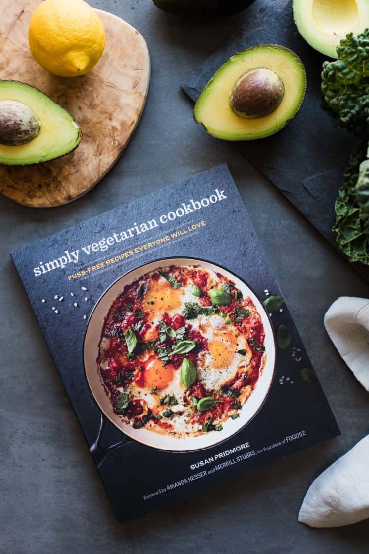 Simply Vegetarian Cookbook on grey table with avocados and kale.