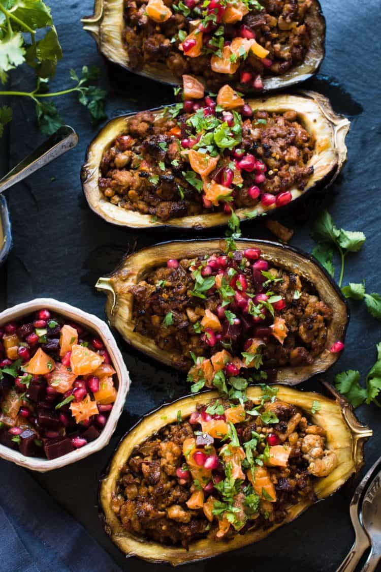Stuffed Eggplant with Meat and Tahini is topped with a bright Orange Pomegranate Salsa on black slate board.