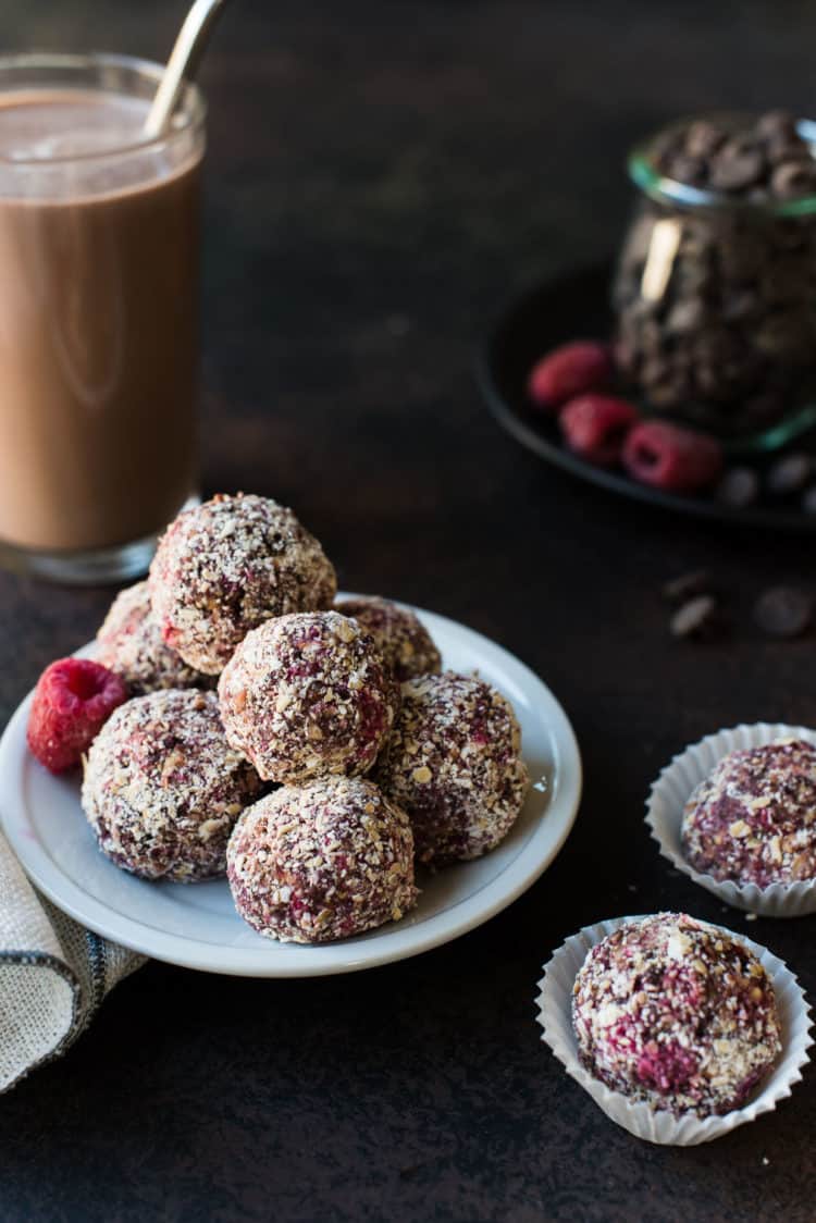Raspberry Peanut Butter Energy Bites with a glass of chocolate milk in the background.
