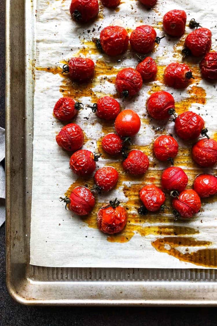 Roasted cherry tomatoes on a baking sheet for Roasted Tomato Pasta Skewers.