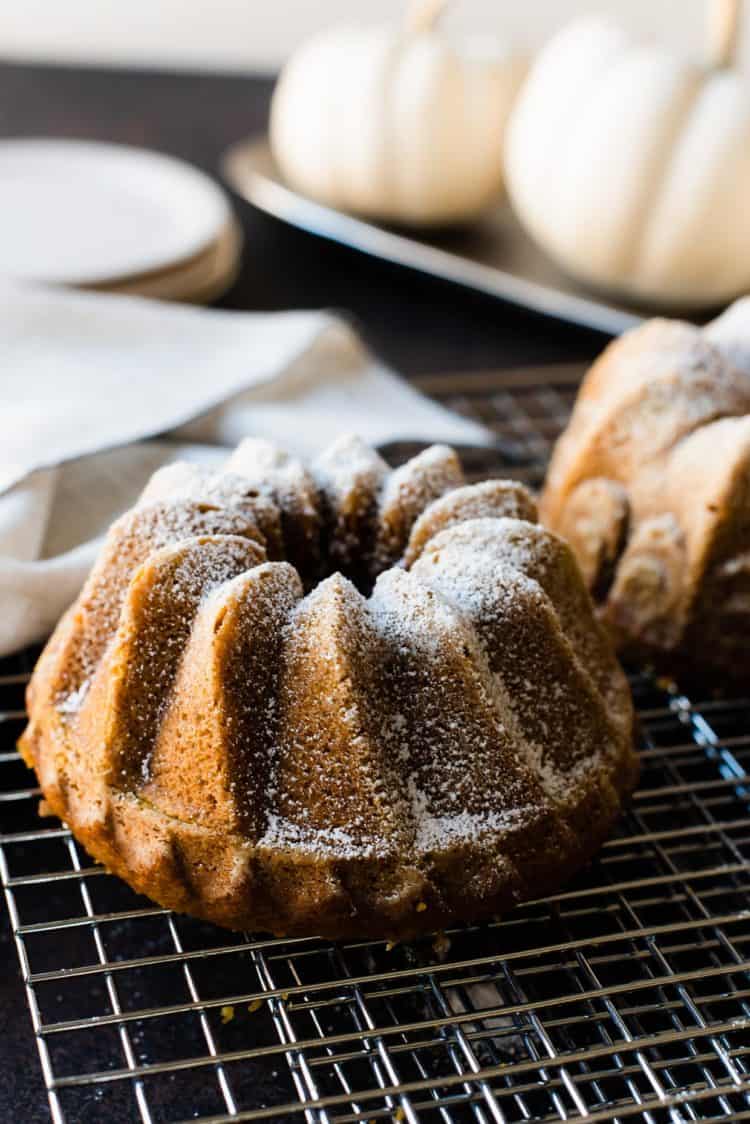 Pumpkin Spice Bundt Cake on a wire rack. White pumpkins in the background.