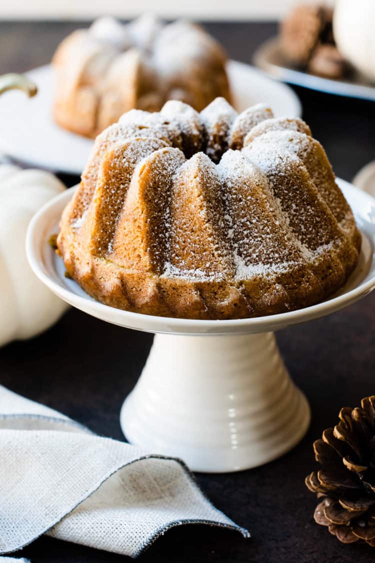 Pumpkin Spice Buttermilk Bundt Cake on cake stand with powdered sugar.