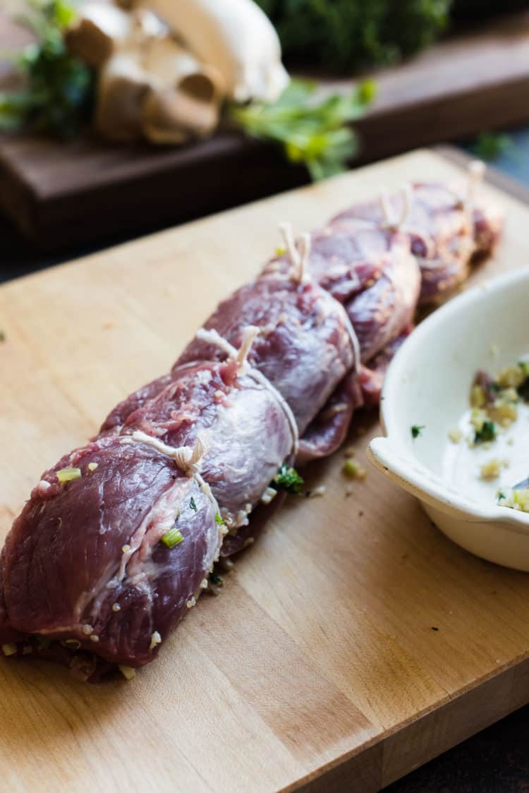 Stuffed and tied Quinoa Stuffed Pork Tenderloin on a cutting board.