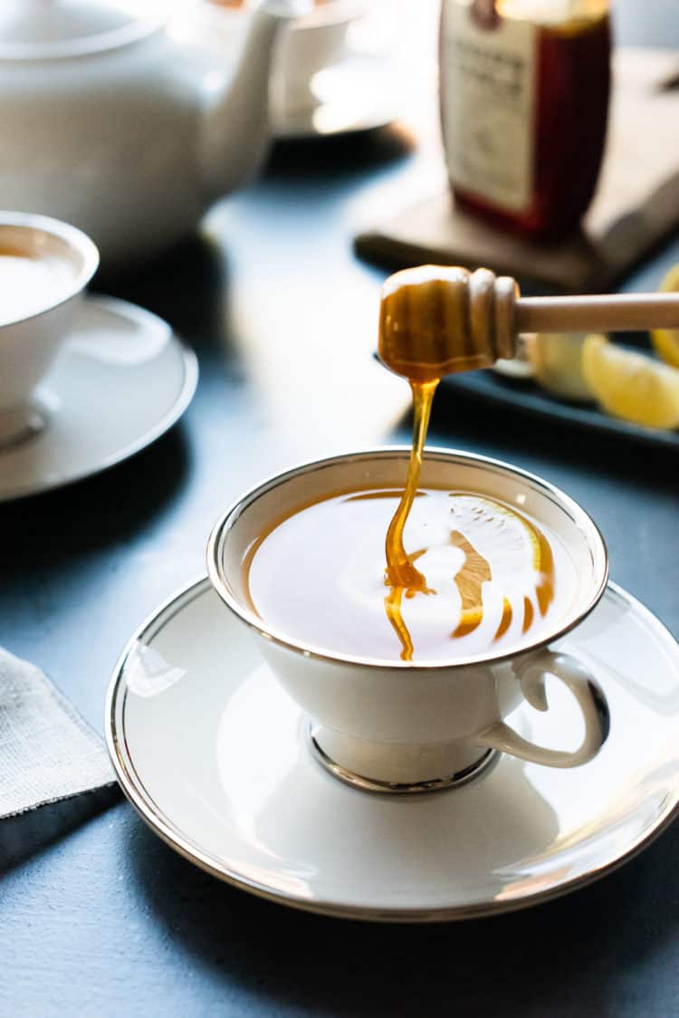 Drizzling honey into a cup of hot liquid.