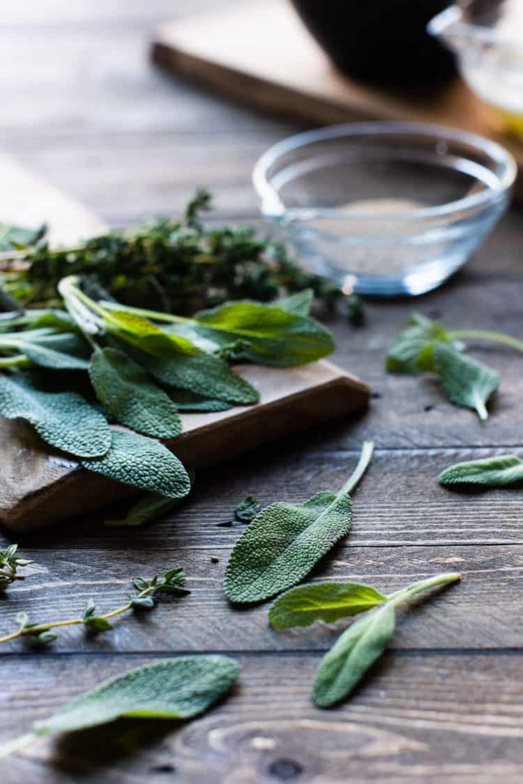 Fresh sage and thyme on a wooden table.