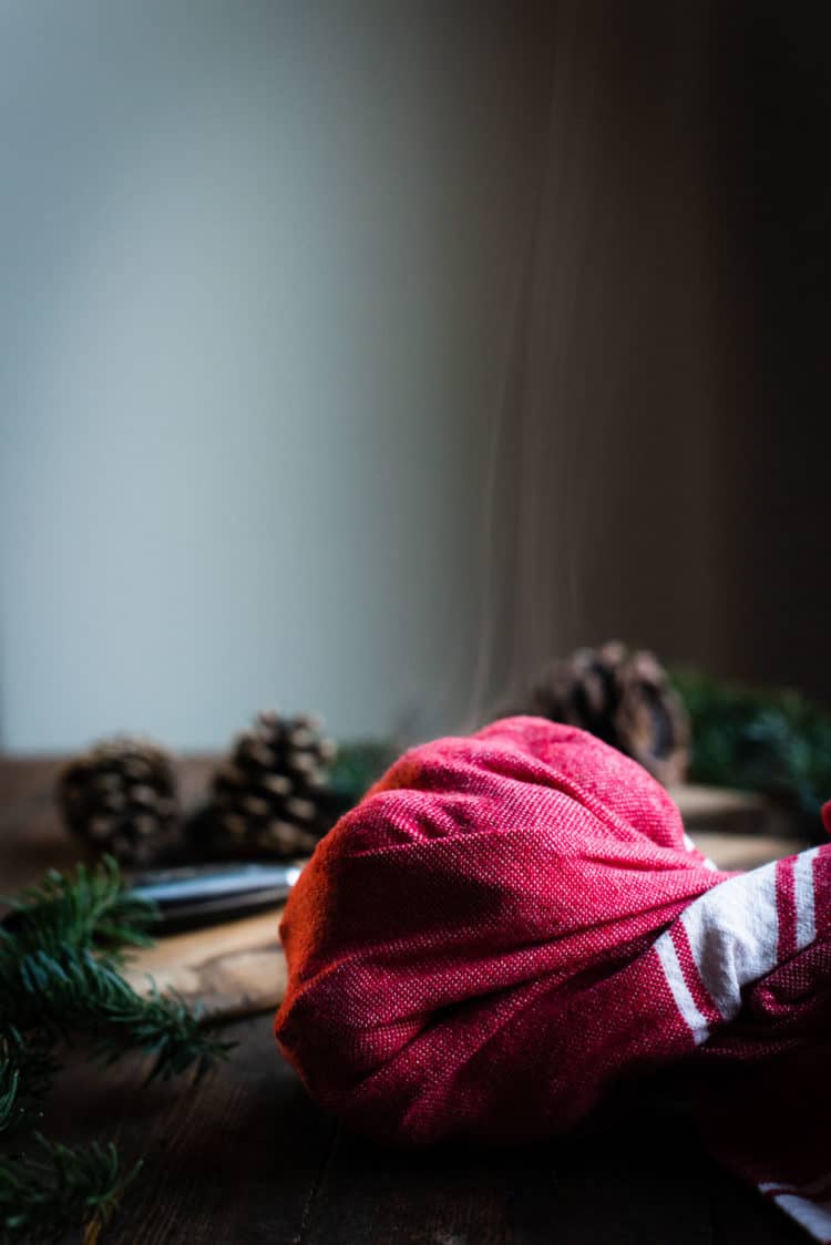 Oven-roasted chestnuts wrapped in a kitchen towel with steam coming out.