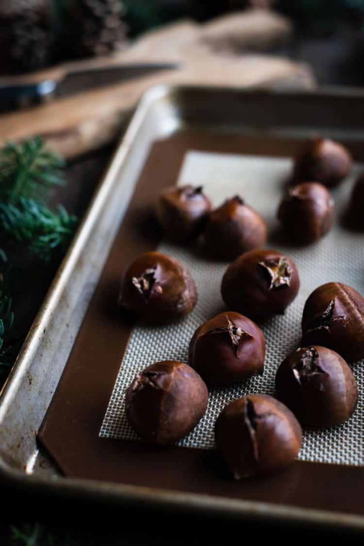Fresh oven-roasted chestnuts on a baking sheet.