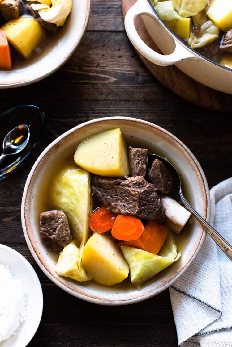 A bowl of Beef Nilaga (Filipino Beef and Vegetable Soup) made in the Instant Pot. Chunks of beef, short ribs, potato, cabbage, carrots, and sweet potato in a bowls.