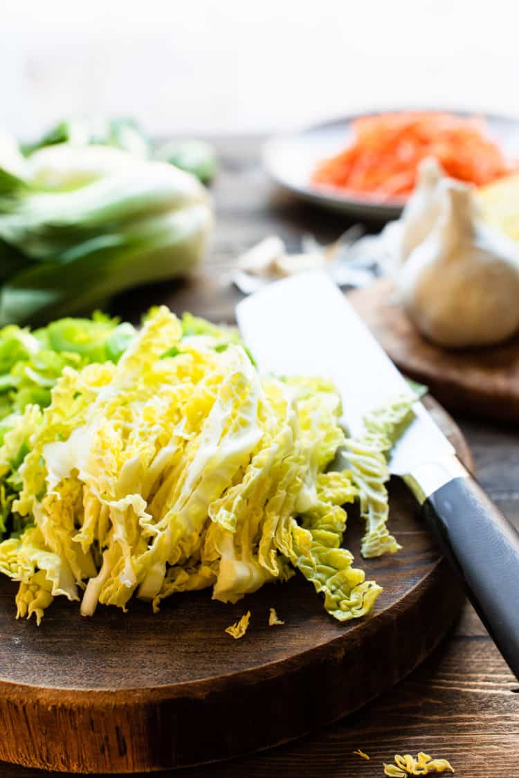 Chopped cabbage on a cutting board with a knife for Pancit Canton.