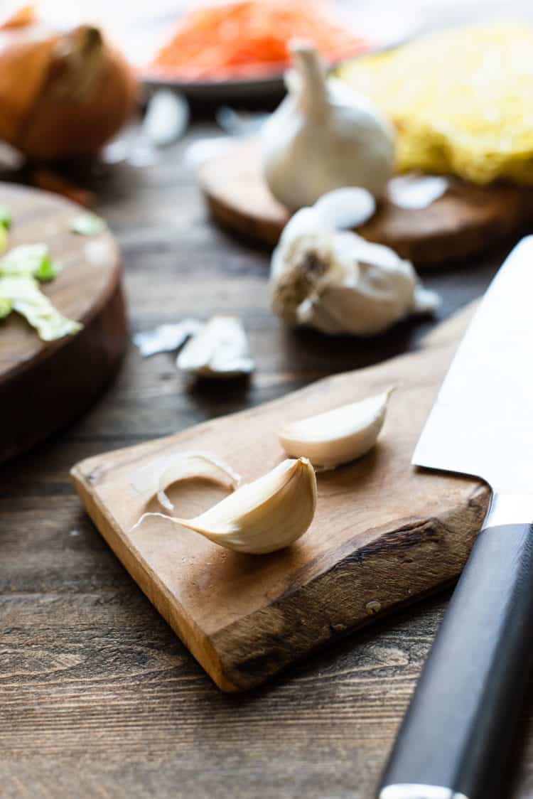 Cloves of garlic on a cutting board for Pancit Canton recipe.