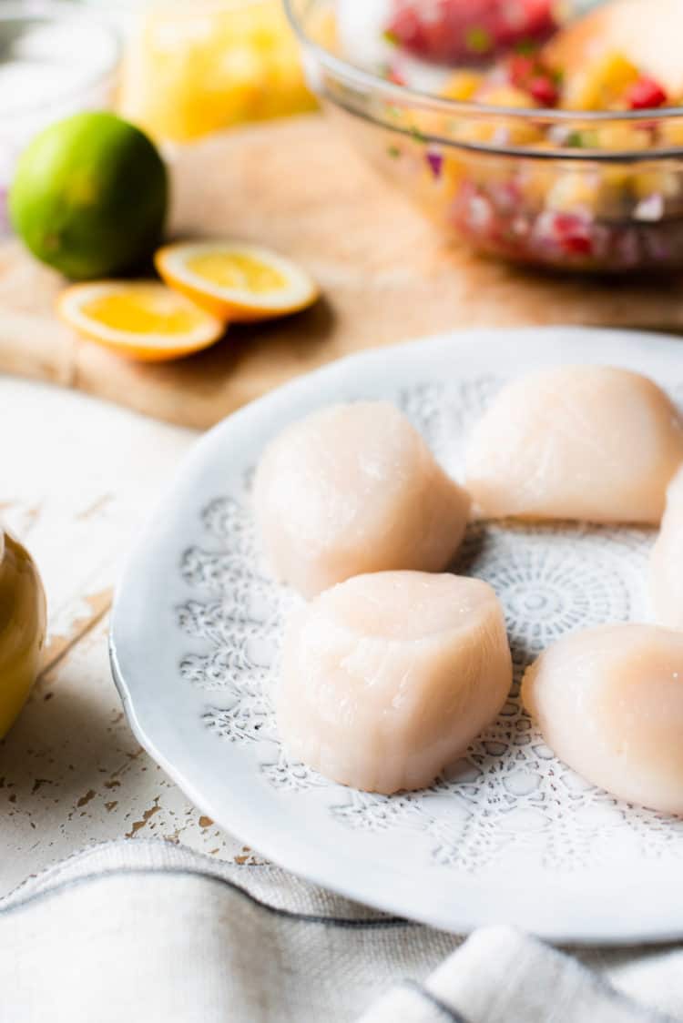 Fresh, raw scallops on a plate for Seared Scallops with Citrus Salsa.