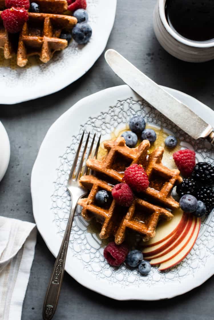 Apple Oatmeal Blender Waffles  on a white plate with fresh berries and apples.