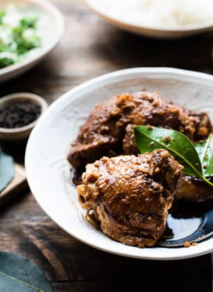 Instant Pot Chicken Adobo in a serving dish garnished with fresh bay leaves.
