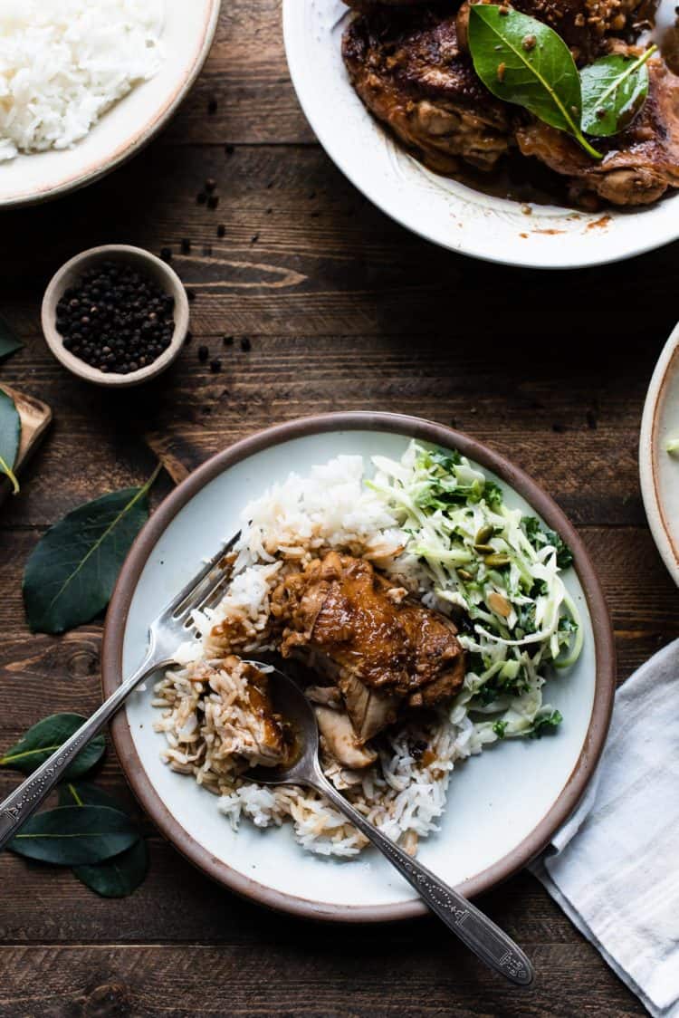 A serving of Instant Pot Chicken Adobo on a plate with rice and vegetables.