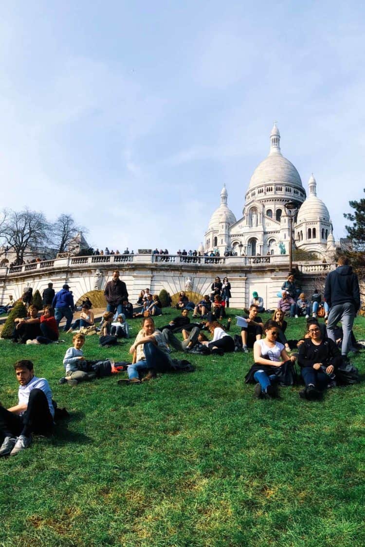 People resting on grass by Sacre Coeur.