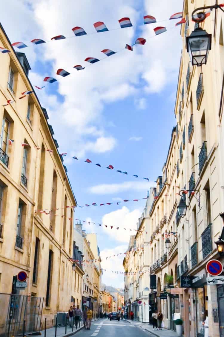 French flags hanging between buildings in Le Marais Paris, France.