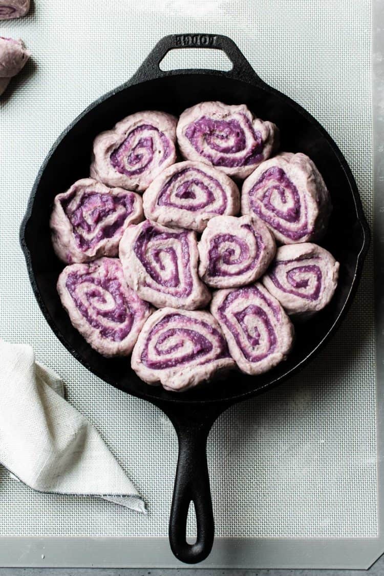 Vegan Coconut Ube rolls ready to bake in a cast iron skillet.