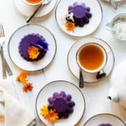 Ube Halaya served with edible flowers on white plates and served with tea.