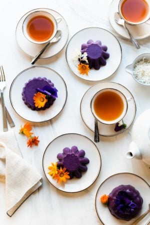 Ube Halaya served with edible flowers on white plates and served with tea.